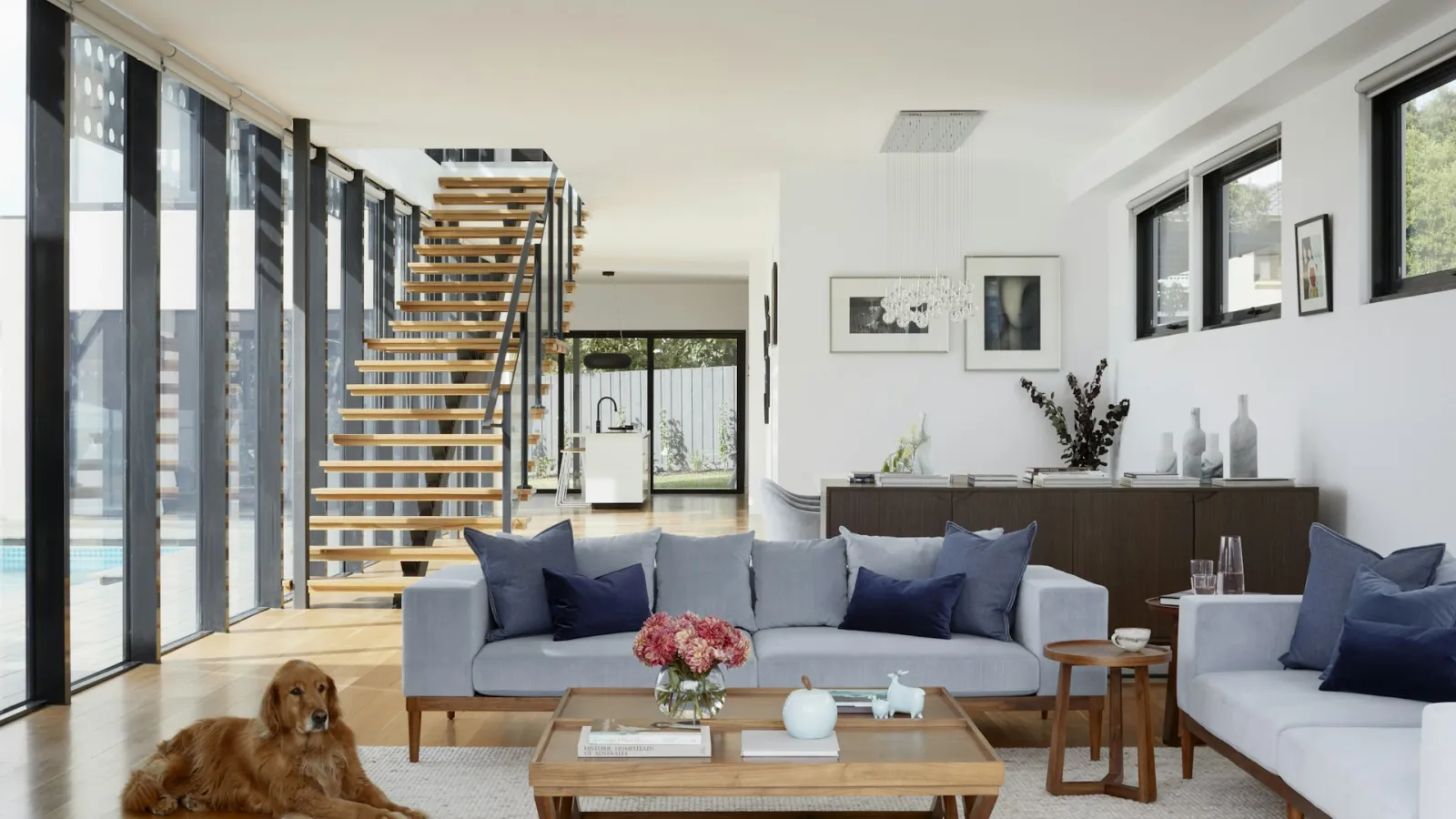 Salón luminoso con escalera abierta y materiales cálidos