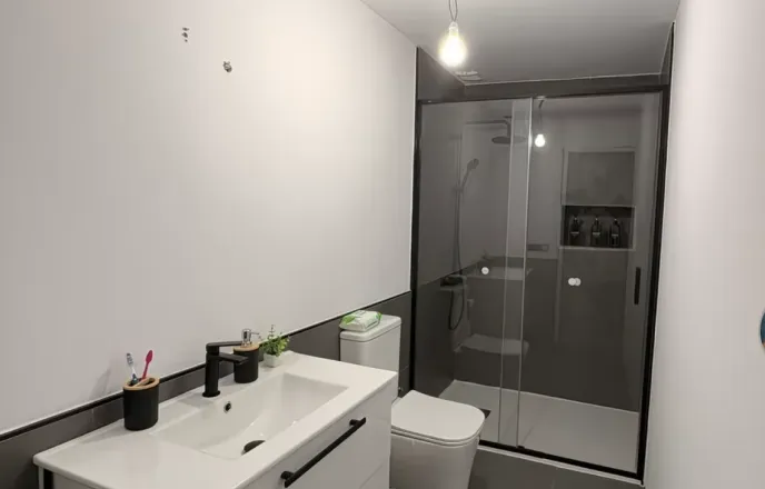 Zona de ducha con mampara y revestimiento cerámico